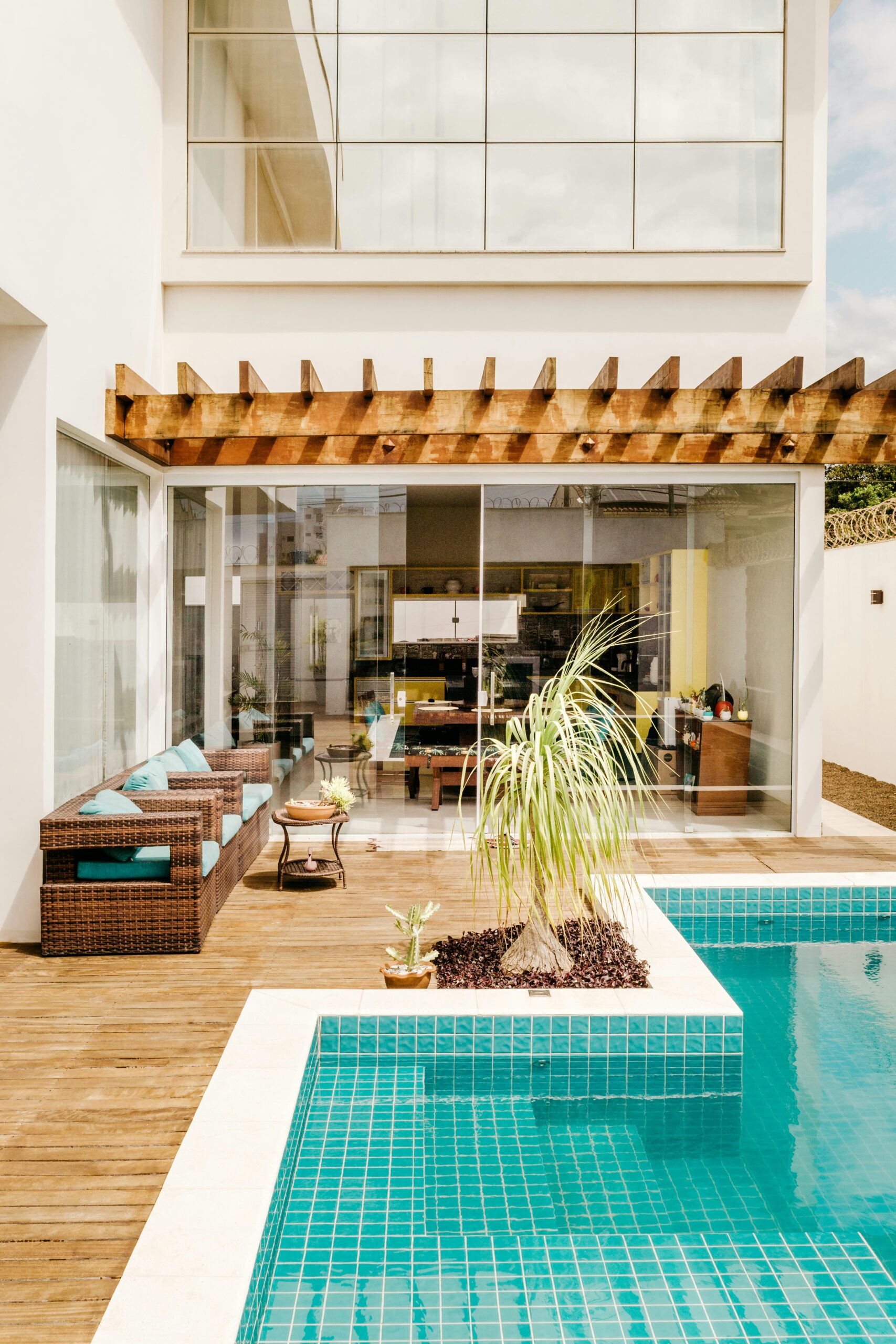 Moderne Poolanlage mit Sitzmöglichkeiten hinter einem Haus mit Glasfassade